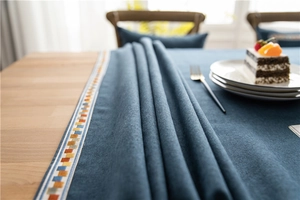 Close-up of deep blue tablecloth with colorful geometric ribbon edge and textured fabric
