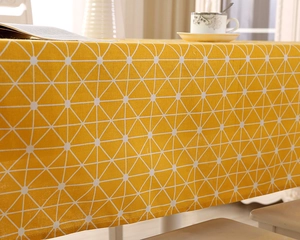 Detail der gelben Tischdecke mit weißem Geometriemuster zeigt Stofffall und Textur