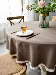 Close-up of dark brown round tablecloth featuring elegant white lace fringe details