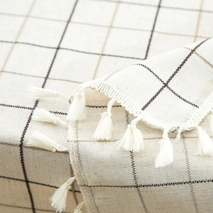 Detailed close-up of geometric plaid tablecloth fabric texture with white tassel fringe