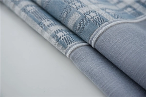 Detail shot of blue linen-textured table runner with precise white stitched edge finish