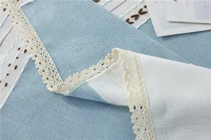 Detailed close-up of light blue jacquard tablecloth with lace trim and geometric embroidery