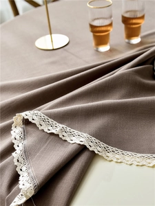 Detailed close-up of linen-textured tablecloth with white crochet lace tassel fringe
