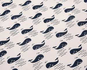 Detailed view of woven linen fabric featuring navy blue whale patterns and waves