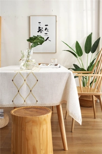 Detail of beige linen tablecloth with yellow diamond embroidery and lace trim border