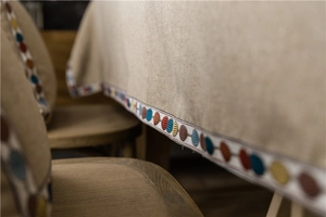 Detail of bohemian khaki tablecloth featuring colorful circular embroidered lace borders