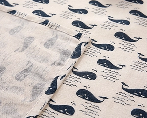 Close-up of minimalist cotton linen tablecloth featuring blue whale patterns and neat stitching