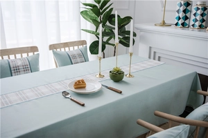 Close-up of waterproof faux linen table runner with geometric mint green and plaid design