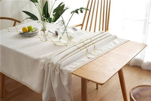 Close-up of geometric diamond embroidery and delicate lace edge on a beige tablecloth