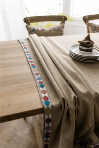 Close-up of linen blend tablecloth with colorful embroidered dot lace and natural texture