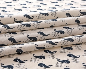 Close-up detail of thick cotton-linen fabric with blue whale pattern and wave lines