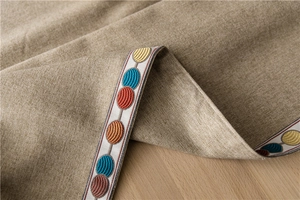 Macro detail of khaki poly-cotton tablecloth with colorful round embroidered lace edge