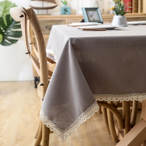 Close-up of grey-brown linen tablecloth with elegant white crochet lace fringe details