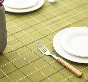 Detail of green plaid tablecloth featuring fine woven texture and decorative tassel trim
