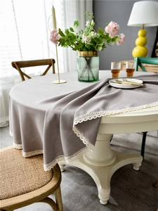 Detailed close-up of grey linen-style round tablecloth with elegant white lace fringe edges