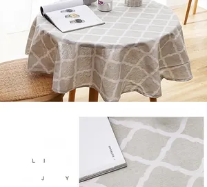 Detail of round linen-style tablecloth with beige clover pattern and clean stitching
