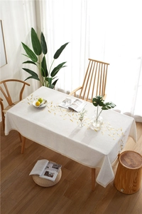 Detailed close-up of leaf embroidery and lace edge on the beige linen tablecloth