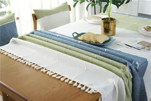 Macro detail of Nordic plaid tablecloth featuring elegant white tassel fringes and linen texture