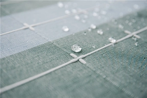 Close-up of waterproof plaid table runner fabric with clear water droplets on surface