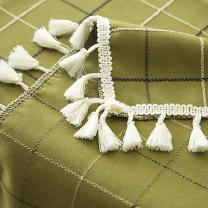 Close-up of green checkered tablecloth featuring white tassels and woven texture