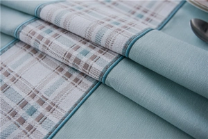 Macro shot of waterproof faux linen table runner with geometric patchwork and blue edging