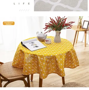 Macro shot of yellow round tablecloth with white triangle pattern and tassel edge detail