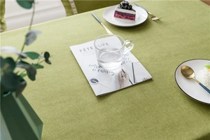 Detail view of sage green faux linen tablecloth with woven texture and premium place setting