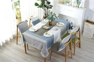 Detail of blue and grey geometric tablecloth with white pom-pom fringe and matching chair covers