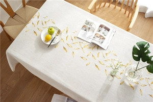 Detail of waterproof beige linen tablecloth with yellow leaves and lace edges