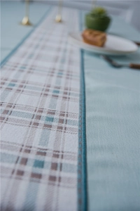 Detail of light blue plaid table runner showing high-quality stitching and linen texture