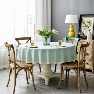 Close-up of mint green round tablecloth with elegant cream lace edges on a wooden table