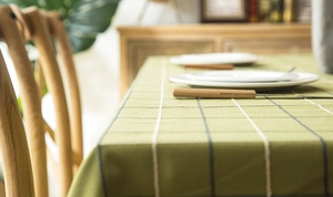 Detail of green plaid tablecloth featuring textured weave and elegant fringed edges