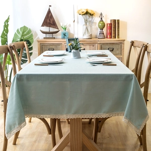 Close-up of light green linen tablecloth featuring delicate white lace edge trim