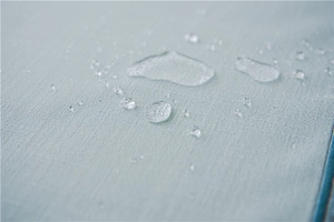 Macro shot of waterproof light blue faux linen fabric with crystalline water droplets