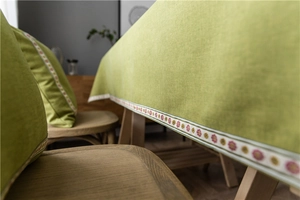 Close-up of green cotton linen tablecloth with floral embroidery and natural texture