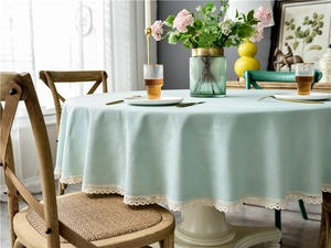 Macro detail of mint green linen-textured round tablecloth with white lace tassel edges