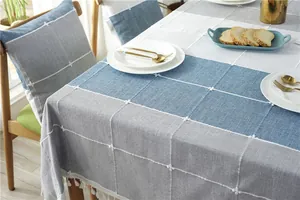 Detail of Nordic grey and blue plaid tablecloth with floral embroidery and tassel fringe