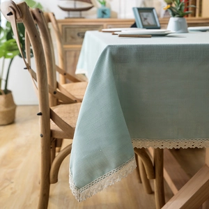 Detail of mint green tablecloth with white crochet lace border on a wooden table
