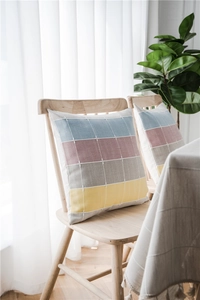 Detail of color-block checkered cushion covers in cotton linen on a wooden chair