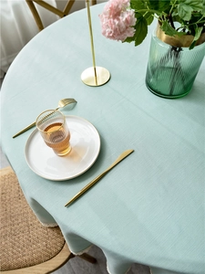 Detail of mint green linen texture tablecloth with elegant wavy lace edges on a round table