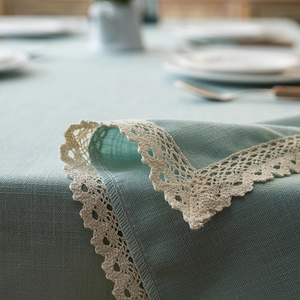 Macro detail of teal linen tablecloth with intricate white crochet lace edge and texture