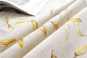 Detail of waterproof tablecloth fabric with golden leaf embroidery on linen texture