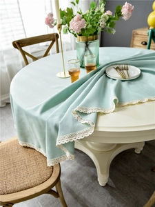 Detail of mint green round tablecloth with white lace trim in a cozy home setting