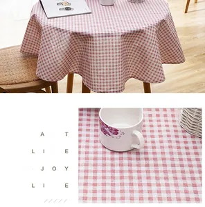 Detailed macro shot of pink gingham linen-style tablecloth with fringe on round dining table