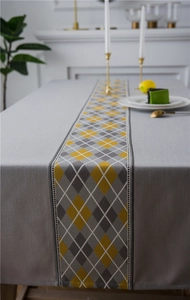 Close-up of waterproof faux linen table runner with yellow and grey argyle pattern