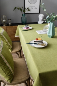 Detail of avocado green linen tablecloth featuring colorful floral woven ribbon borders