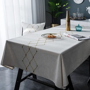 Detailed close-up of gold geometric embroidery on waterproof beige linen tablecloth