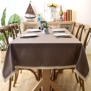 Detail of waterproof brown table cloth with white crochet lace border on wooden table