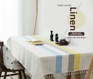 Close-up of linen tablecloth with yellow, gray, blue stripes and white fringe tassels