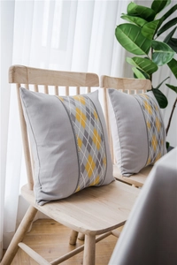 Close-up of modern grey linen pillow with yellow diamond pattern on a wooden chair